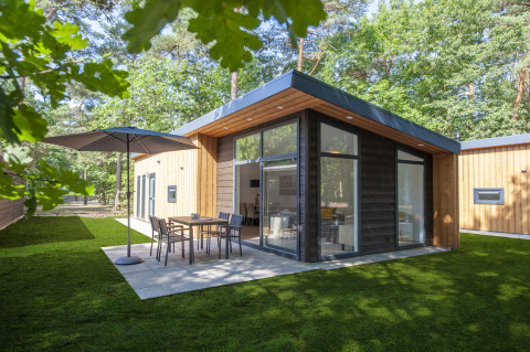 Tiny house moderna Lodge 6 al Bospark 't Wolfsven nei Paesi Bassi, con patio, tavolo da pranzo e vista sul bosco.