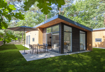 Moderne tiny house Lodge 6 i Bospark 't Wolfsven, Nederlandene, med terrasse og havemøbler omringet af skov.