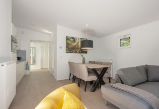 Bright and modern tiny house interior at Lodge 6, Bospark 't Wolfsven, with sofa, dining table, and kitchen.