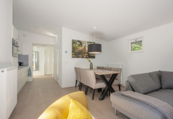 Lyst og moderne interiør af et lille hus på Lodge 6, Bospark 't Wolfsven, med sofa, spisebord og køkken.