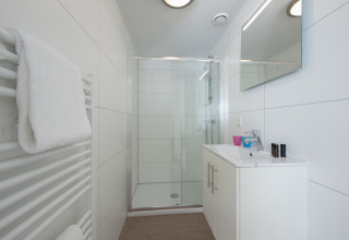 Modernes, kompaktes Badezimmer mit Dusche, Waschbecken und Handtuch in Lodge 6, Bospark 't Wolfsven, Niederlande.
