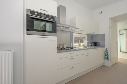 Modern compact kitchen in Lodge 6 at Bospark 't Wolfsven, Netherlands, with white cabinets and sleek appliances.