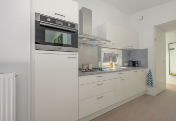 Modern compact kitchen in Lodge 6 at Bospark 't Wolfsven, Netherlands, with white cabinets and sleek appliances.