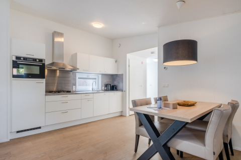 Cucina moderna e zona pranzo compatta in una Lodge 4 al Bospark 't Wolfsven, Paesi Bassi, interni chiari.