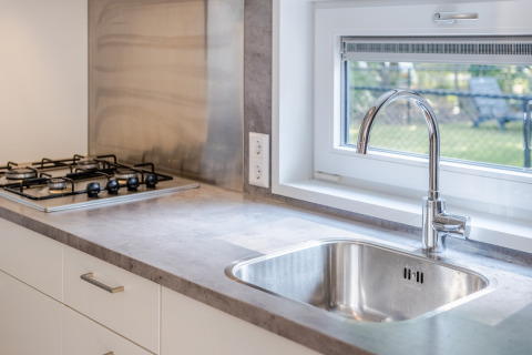Moderno lavello e piano cottura a gas con finestra nella cucina compatta di Lodge 4, Bospark 't Wolfsven, Paesi Bassi.