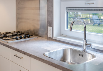 Moderne køkkenvask og gaskomfur i et kompakt køkken med vindue i Lodge 4, Bospark 't Wolfsven, Holland.