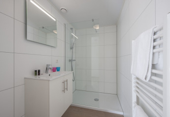 Modern white bathroom with shower, mirror, and towel heater at Lodge 4, Bospark 't Wolfsven, Netherlands.