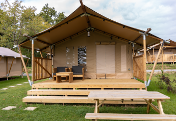 Safari tent Comet 27 Lodges met overdekte veranda, tuinmeubels en picknicktafel op het gras.
