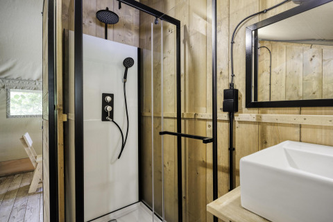 Salle de bain moderne avec cabine de douche et lavabo dans la tente safari Comet 27 Lodges, Arden Parks, France.