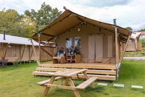 Dos personas descansan frente a una tienda safari en Comet 27 Lodges, Arden Parks, Signy l'Abbaye, Francia.