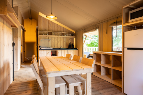 Interior de la tienda safari Dreamer 49 en Arden Parks, Signy l'Abbaye, Francia, con muebles de madera y cocina.