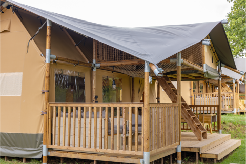 Safari-Zelt Ranger Lodge mit überdachter Veranda, Holzgeländer und Treppe zu erhöhtem Bereich.