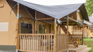 Safari-Zelt Ranger Lodge mit überdachter Veranda, Holzgeländer und Treppe zu erhöhtem Bereich.