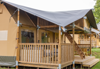 Tenda safari Ranger Lodge con veranda coperta, balaustra in legno e scala verso l’area superiore.