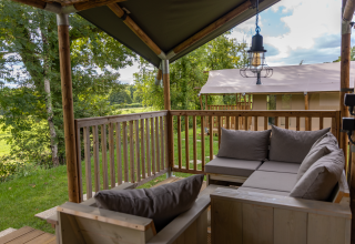 Blick von der überdachten Terrasse mit Sofas am Ranger Lodge Safarizelt in Arden Parks, Frankreich.