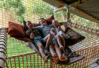Tre bambini felici si rilassano su una rete con cuscini nella tenda safari Ranger Lodge a Signy l'Abbaye, Francia.