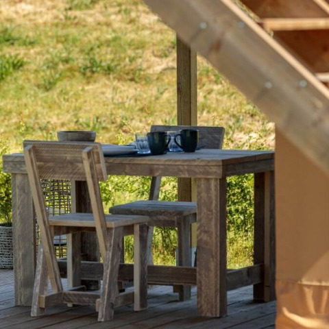 Table et chaises en bois rustique sur une terrasse d’une tente safari à Arden Parks, Signy l'Abbaye, France.