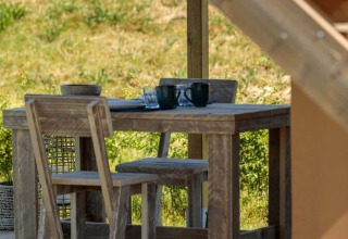 Table et chaises en bois rustique sur une terrasse d’une tente safari à Arden Parks, Signy l'Abbaye, France.
