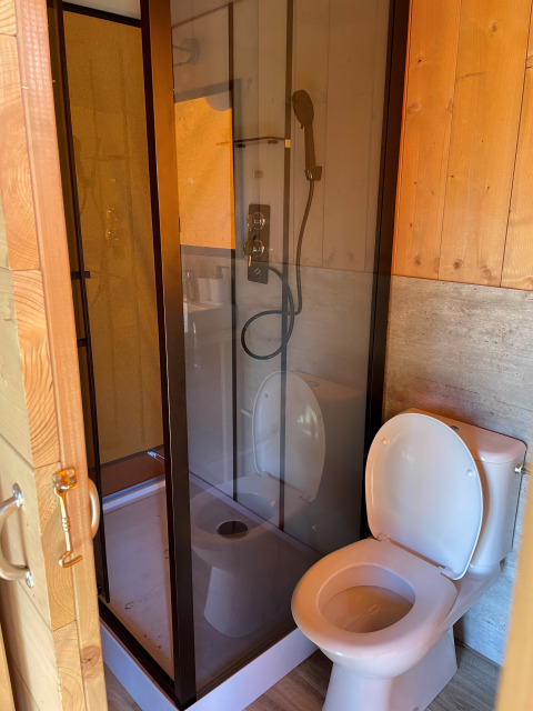 Salle de bain dans une tente safari à Arden Parks, Signy l’Abbaye : douche fermée et toilettes voisines.