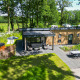 Moderne træhytte, omgivet af grøn natur, med terrasse, boblebad og spisebord i haven ved Wood Cottage.