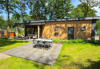 Moderne Wood Cottage ved Camping de Witte Berg i Holland med udendørs spiseplads og grøn have.