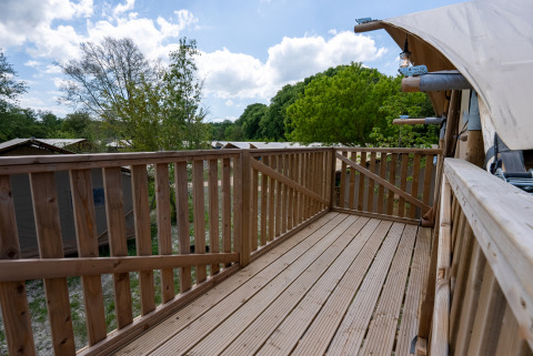 Terrazza in legno della tenda Safari 2 a Lauwersmeer, Paesi Bassi, con vista su alberi e tende vicine.
