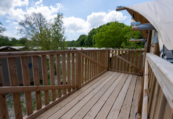 Terraza de madera del Safari tent 2 en Lauwersmeer, Países Bajos, con vistas a árboles y otras tiendas.