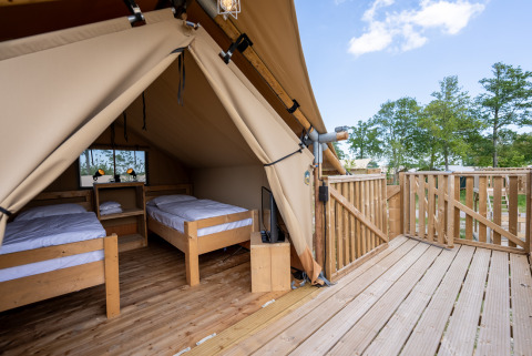 Interno della Safari tent 2 a Lauwersmeer, Paesi Bassi, con due letti singoli e terrazza in legno.