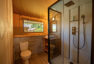 Baño dentro de la tienda Safari 4 en Lauwersmeer, Países Bajos, con ducha, inodoro y lavabo moderno.
