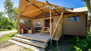 La tienda safari 6 en Lauwersmeer, Países Bajos, tiene una gran terraza con muebles de madera y naturaleza.