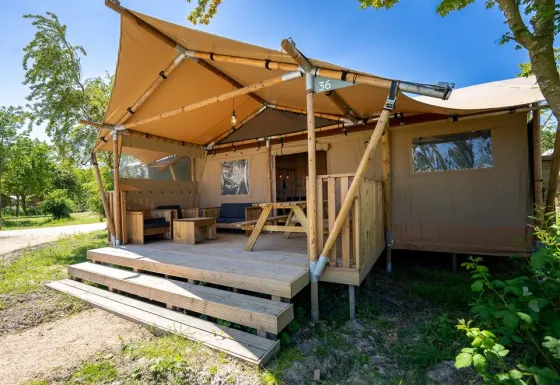 La tienda safari 6 en Lauwersmeer, Países Bajos, tiene una gran terraza con muebles de madera y naturaleza.