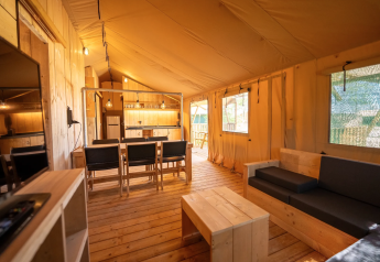 Interior de la tienda Safari 6 en Lauwersmeer, Países Bajos, con muebles de madera y cocina equipada.