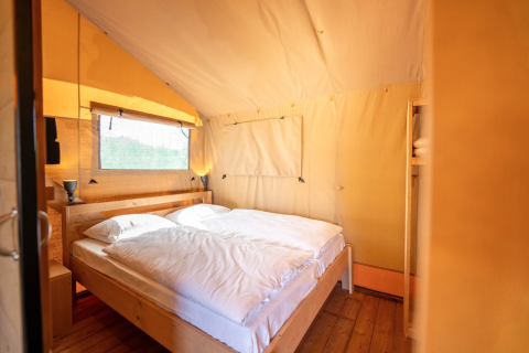 Interno della tenda Safari 6 a Lauwersmeer nei Paesi Bassi, con letto matrimoniale e pavimento in legno.