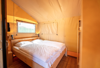 Interior del Safari tent 6 en Lauwersmeer, Países Bajos, con cama doble y suelo de madera.
