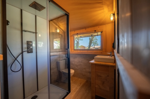Bagno nella tenda Safari 6 al Lauwersmeer nei Paesi Bassi con doccia, lavabo e ampia finestra.