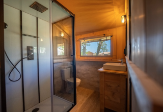 Bagno nella tenda Safari 6 al Lauwersmeer nei Paesi Bassi con doccia, lavabo e ampia finestra.