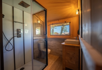 Baño dentro de la tienda Safari 6 en Lauwersmeer, Países Bajos, con ducha, lavabo y ventana.