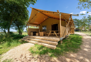 Tenda safari 8 al Lauwersmeer nei Paesi Bassi con veranda in legno, tavolo e natura circostante.