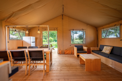 Vista del interior de la tienda Safari 8 en Lauwersmeer, Países Bajos, con muebles de madera y gran espacio.