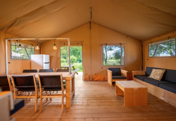 Interno della tenda Safari 8 a Lauwersmeer, Paesi Bassi, con arredi in legno e spazio confortevole.