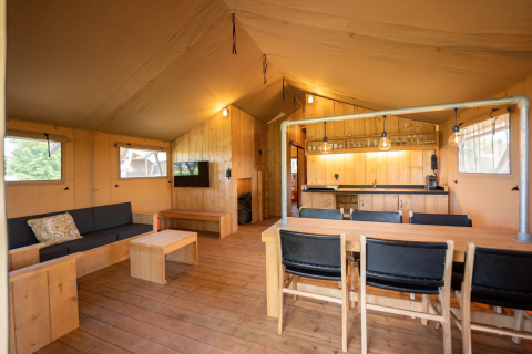 Interno della tenda Safari 8 a Lauwersmeer, Paesi Bassi, con arredi in legno e angolo cucina accogliente.