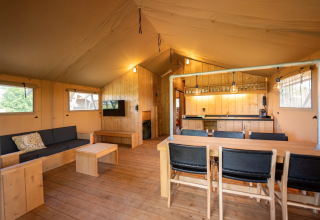 Interior de la tienda Safari 8 en Lauwersmeer, Países Bajos, con muebles de madera y cocina acogedora.