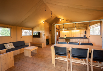 Interno della tenda Safari 8 a Lauwersmeer, Paesi Bassi, con arredi in legno e angolo cucina accogliente.