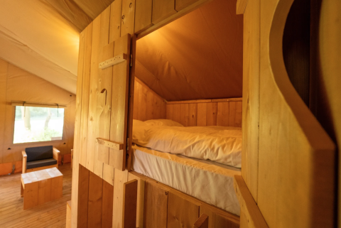 Vista interna della tenda Safari 8 a Lauwersmeer, Paesi Bassi, con arredi e letto in legno accoglienti.