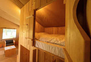 Vista interna della tenda Safari 8 a Lauwersmeer, Paesi Bassi, con arredi e letto in legno accoglienti.