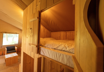 Vista interna della tenda Safari 8 a Lauwersmeer, Paesi Bassi, con arredi e letto in legno accoglienti.