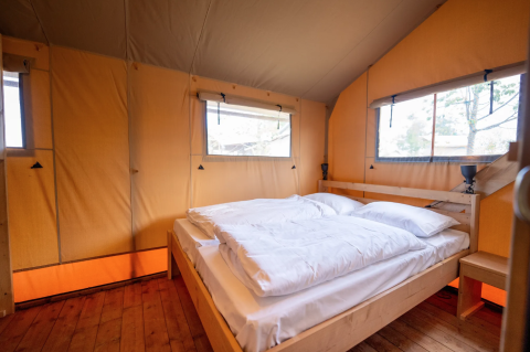 Dormitorio con cama doble en una tienda safari de lujo en Lauwersmeer, Países Bajos, con luz natural.
