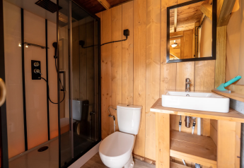 Bagno rivestito in legno con doccia, WC e lavabo nella tenda Safari 8 a Lauwersmeer, Paesi Bassi.