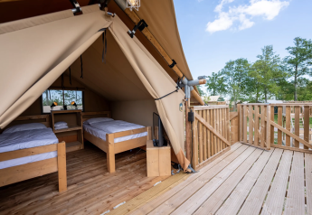 Tienda safari con dos camas individuales sobre terraza de madera en Lauwersmeer, Países Bajos, al aire libre.
