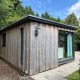 Außenaufnahme der Private Lodge Nummer 26 mit Holzverkleidung und großen Fenstern im Grünen.